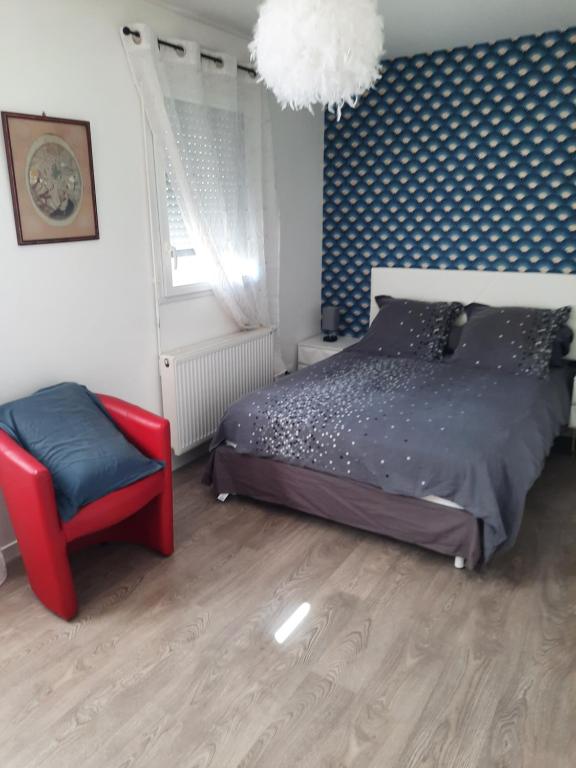 um quarto com uma cama e uma cadeira vermelha em la conviviale em Bénouville