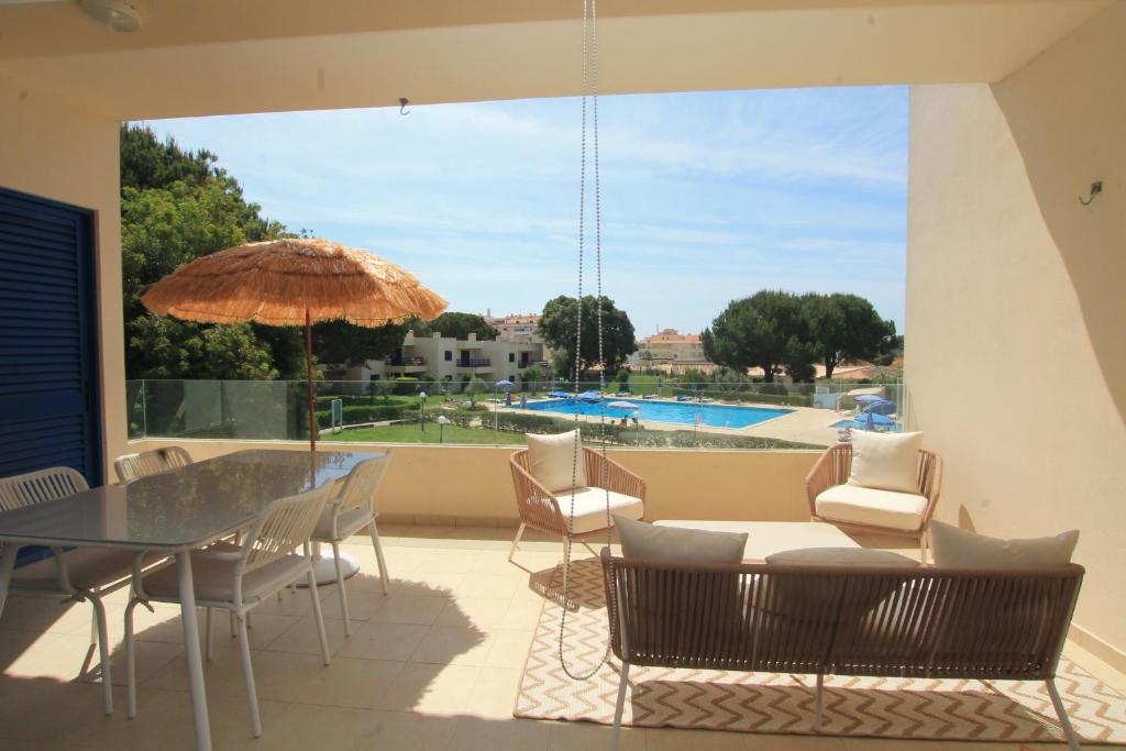 een patio met een tafel en stoelen en een parasol bij Aldeamento Bemposta - Pool & Garden Bemposta in Alvor