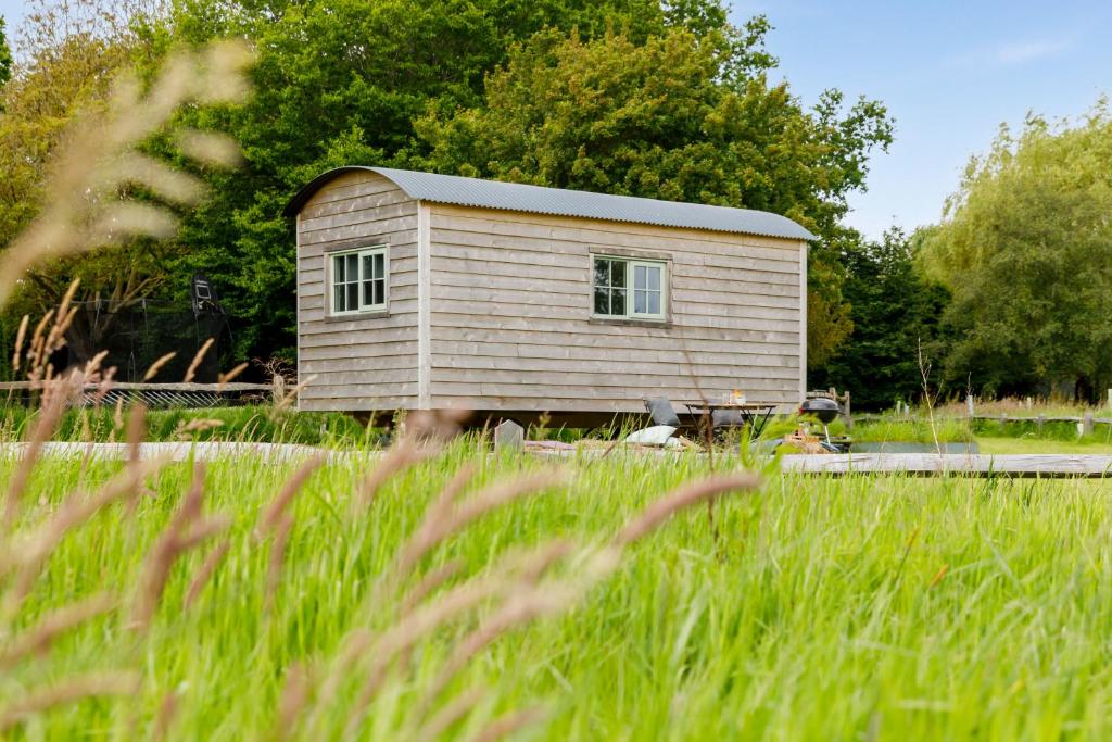 un petit bâtiment dans un champ d'herbe haute dans l'établissement The Witterings Shepherds’ Hut, à West Wittering