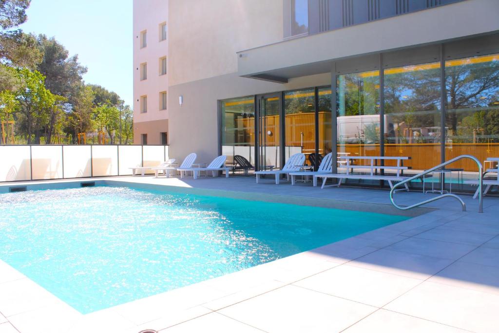 a swimming pool with chairs and a building at Adonis le Castellet in Signes