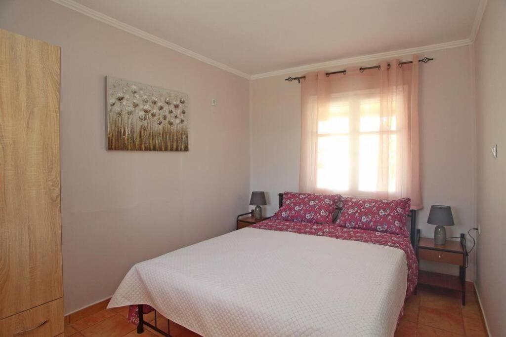 a bedroom with a bed with red pillows and a window at Olga Home Agios Ioannis Lefkada - Lefkada BnB in Lefkada Town