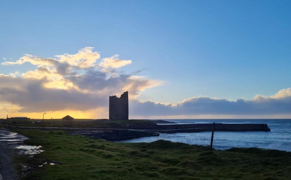 een kasteel op een eiland in het water met de zonsondergang bij Seafront House in Sligo