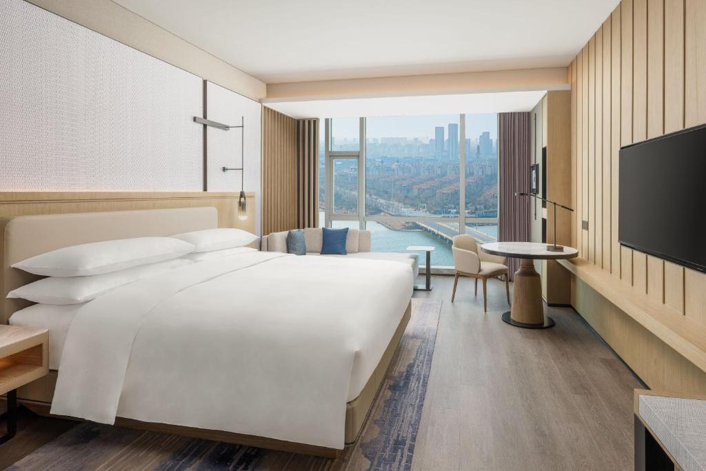 een hotelkamer met een groot bed en een groot raam bij Qingdao Marriott Hotel Jiaozhou in Qingdao