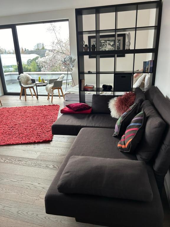 a living room with a brown couch and a red rug at Zum EM Stadion zu Fuß - Luxus im Grünen in Cologne