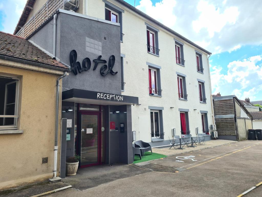 een wit gebouw met een rode deur op een parkeerplaats bij Logis Hôtel du Cirque Troyes centre historique in Troyes