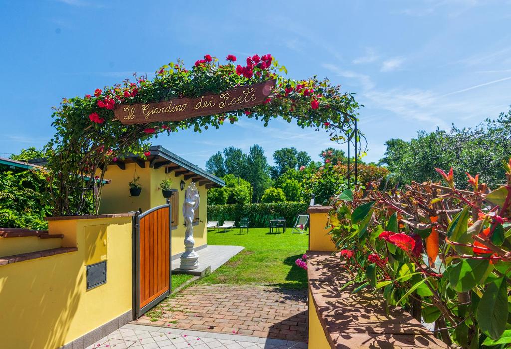 un jardín con un arco de flores con rosas en B&B Il Giardino dei Poeti and Apartaments, en Lucca