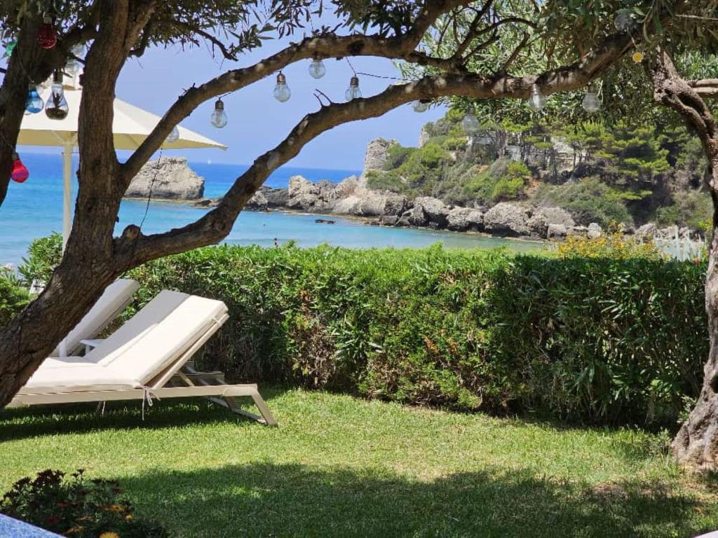 una poltrona bianca sotto un albero vicino all'oceano di Corfu Glyfada Beach Apartment 13 a Glifada (Glyfada)