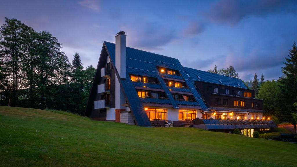 um edifício sobre uma colina com as suas luzes acesas em Wellness Hotel Šedý Vlk em Harrachov