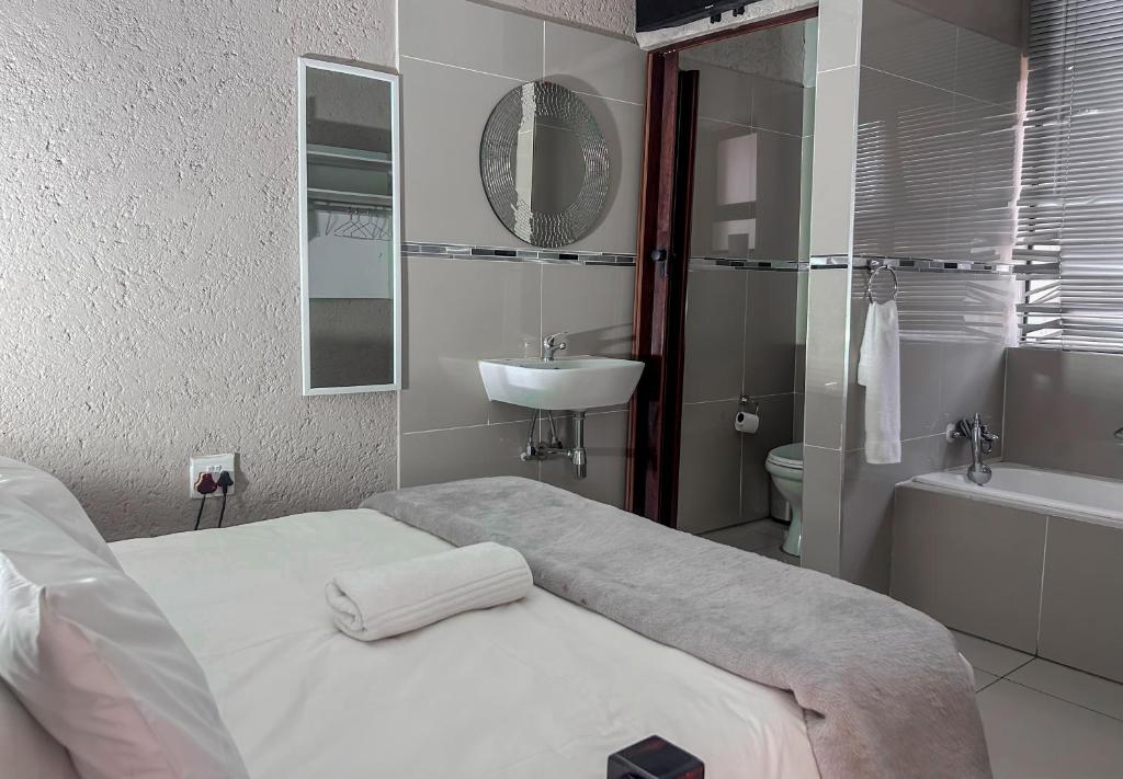 een witte badkamer met een bed en een wastafel bij View Inn Exclusive Lodge in Nelspruit