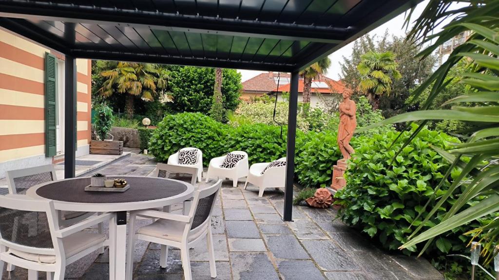 um pátio com uma mesa e cadeiras sob uma pérgola em Villa Marchesa em Arona