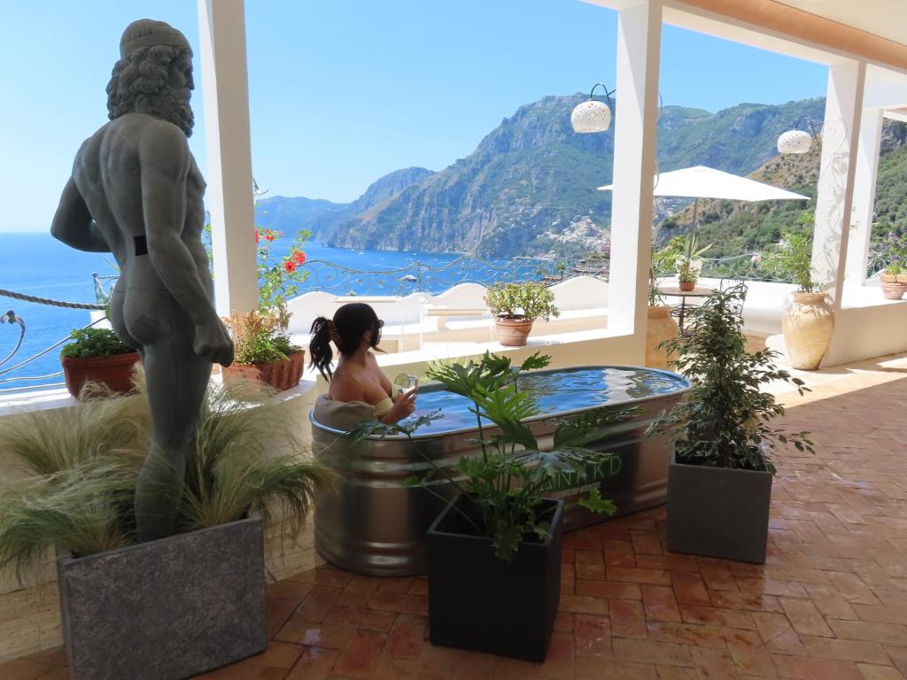 uma mulher numa banheira de hidromassagem numa sala com plantas em Villa Santa Chiara Positano Suites em Positano