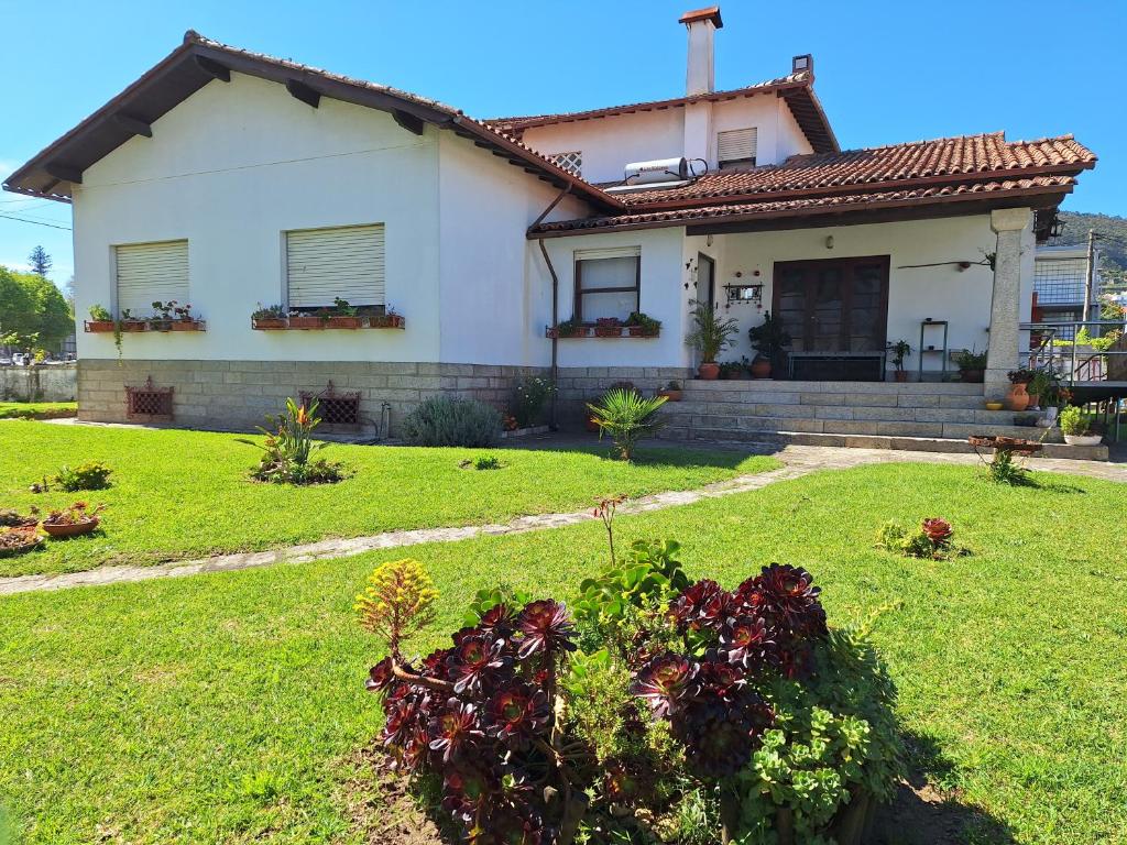 une maison blanche avec une cour en herbe et une cour dans l'établissement Villa Margarida, à Viana do Castelo