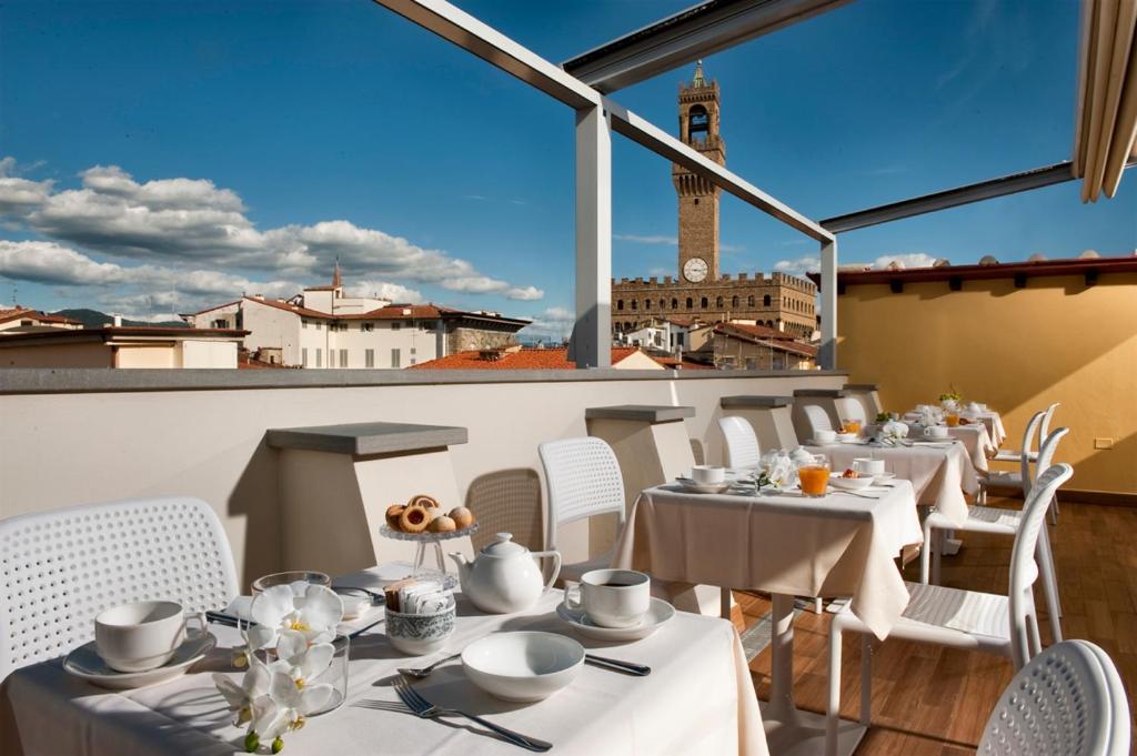 ein Restaurant mit weißen Tischen und Stühlen und einem Uhrturm in der Unterkunft Hotel della Signoria in Florenz