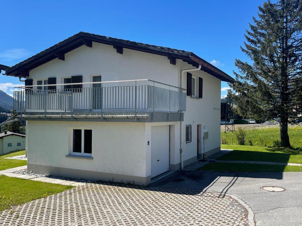 ein weißes Haus mit einem Balkon und einer Auffahrt in der Unterkunft Ski in Ski out Family accommodation Chesa Katja Lenzerheide in Valbella