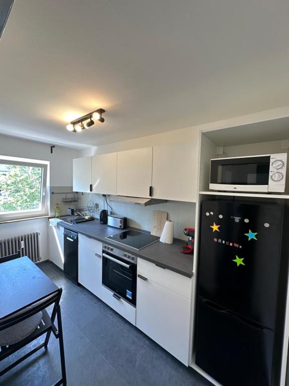 a kitchen with a black refrigerator and white cabinets at Double Bed Apartment - Near Marienplatz in Stuttgart