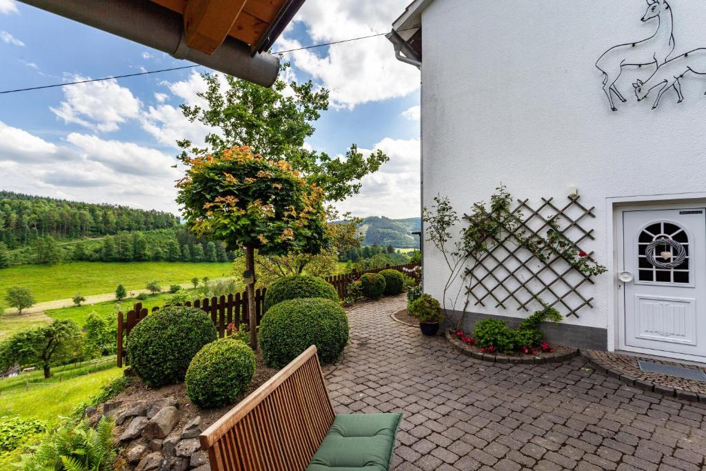 une terrasse d'une maison blanche avec une clôture dans l'établissement Sauerlandblick, à Schmallenberg