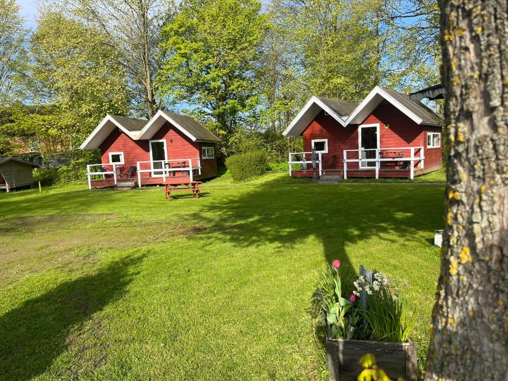 twee rode huisjes in een tuin met een boom bij Hytte C in Gråsten