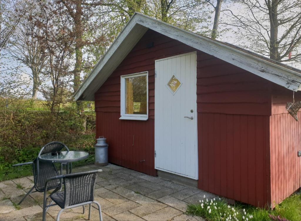 a red shed with a white door and a table at Hytte A in Gråsten