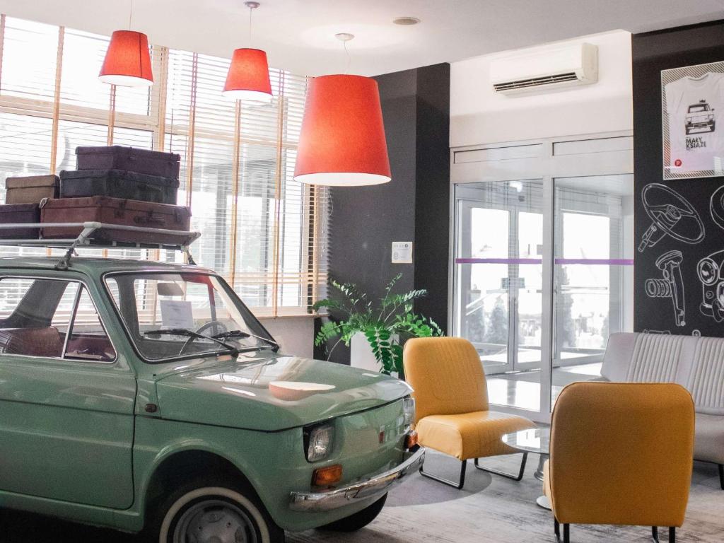 una camera con una vecchia auto verde e sedie arancioni di ibis Styles Bielsko Biala a Bielsko-Biała