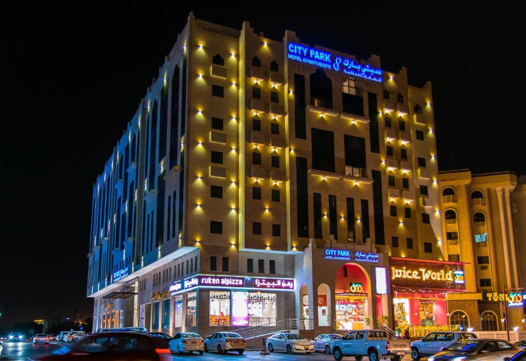 a large building with cars parked in front of it at City Park Hotel Apartments in Muscat