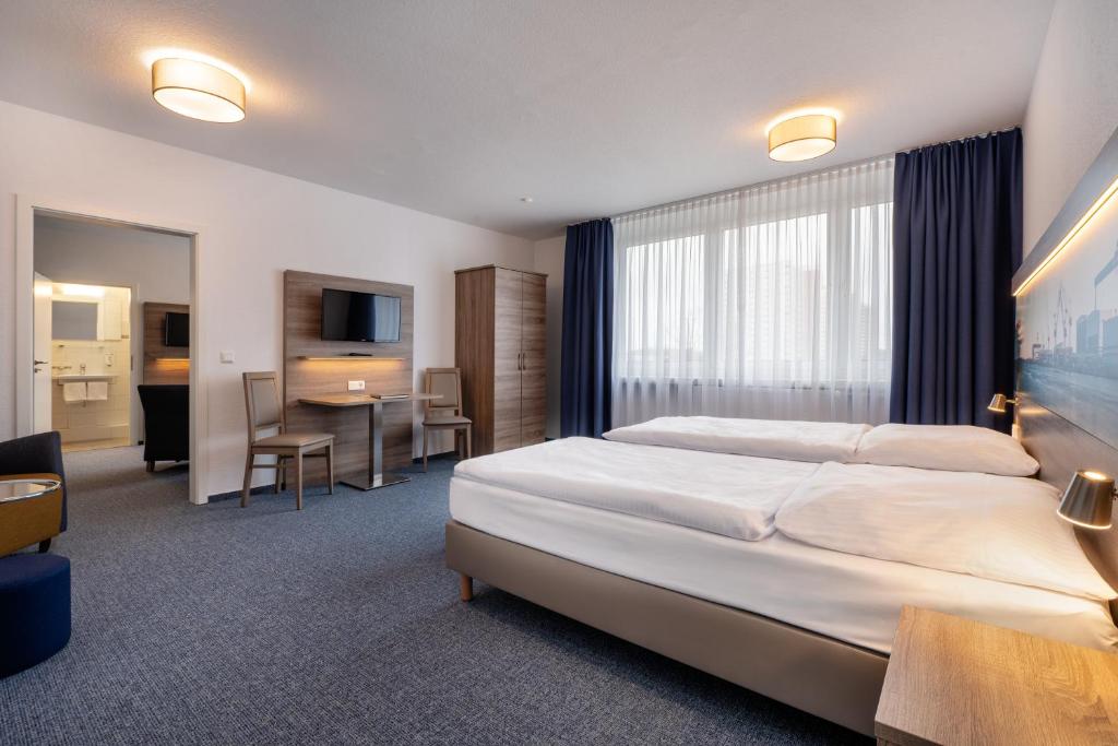 een hotelkamer met een groot bed en een bureau bij Hotel & Gästehaus Rostock Lütten Klein in Rostock