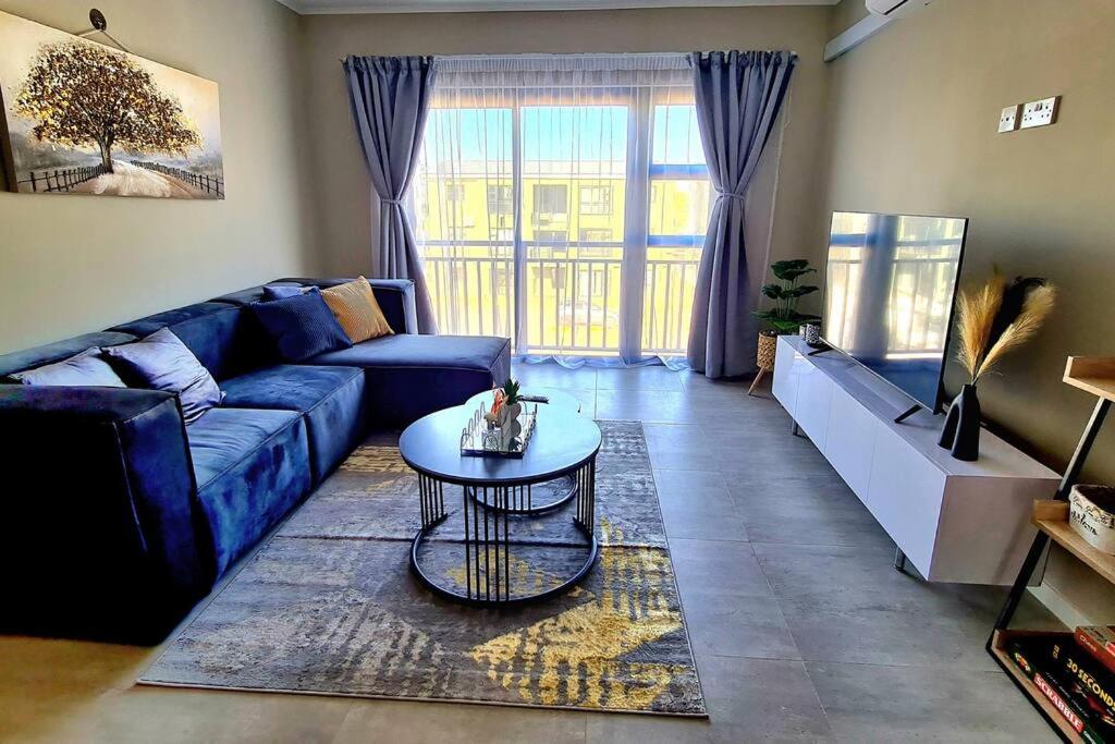 uma sala de estar com um sofá azul e uma mesa em Cozy 1-Bed Apartment in Gaborone em Gaborone