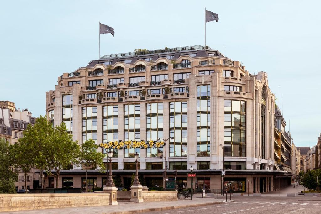 een groot gebouw met twee vlaggen erop bij Cheval Blanc Paris & Dior Spa Cheval Blanc Paris in Parijs