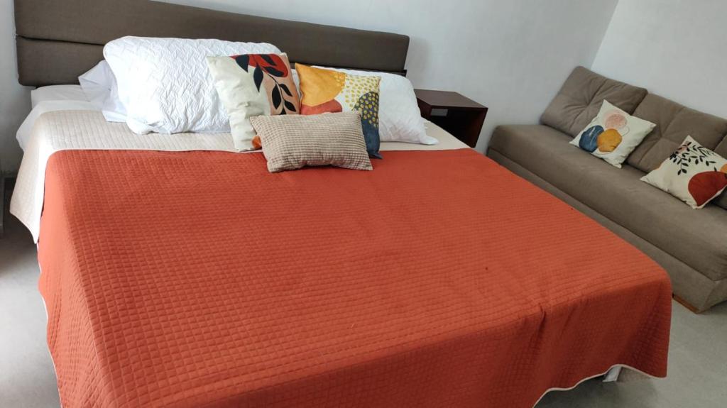 a bed with an orange blanket next to a couch at Villa Baruch in San Juan Cosalá