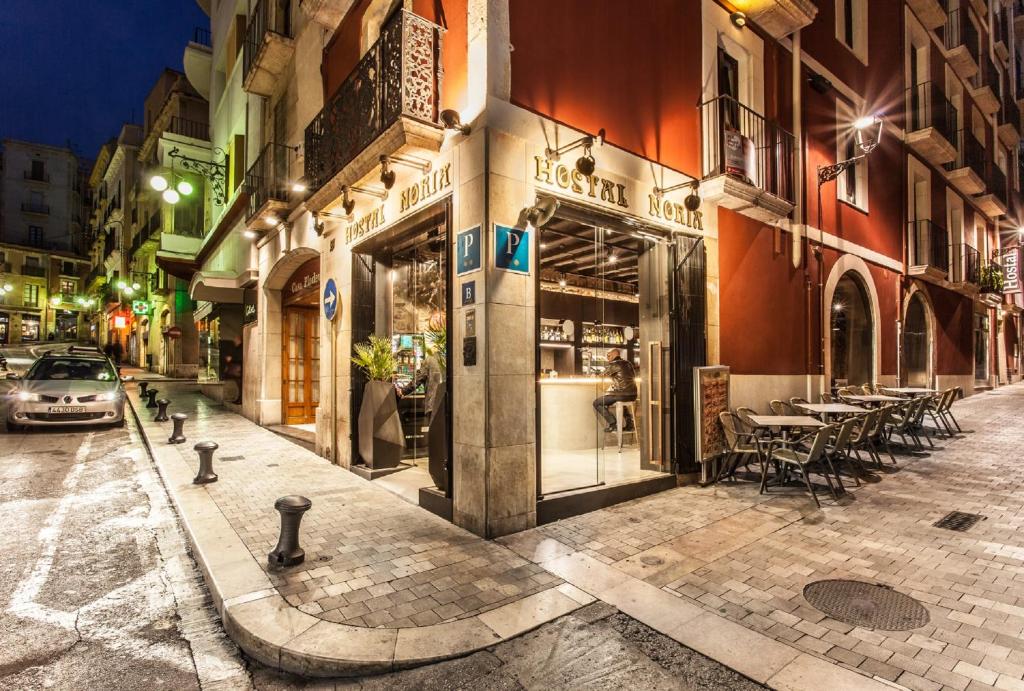 une rue de la ville la nuit avec un restaurant dans l'établissement Hostal Noria, à Tarragone