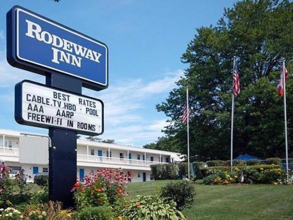 a street sign in front of a building with flags at Rodeway Inn in Rutland