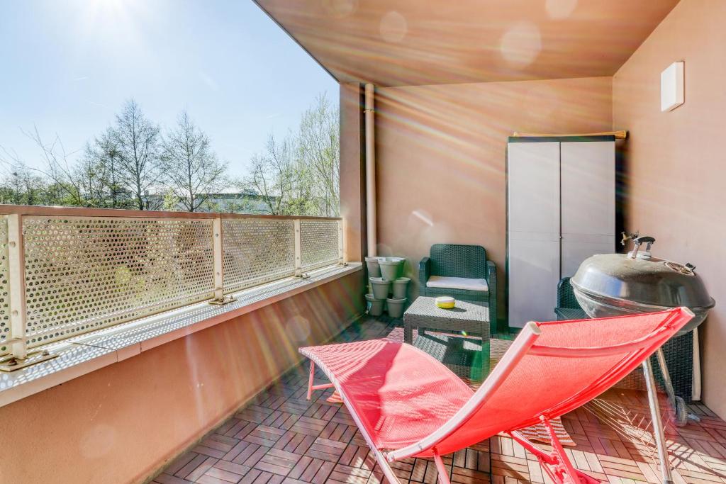 a balcony with a red chair and a grill at "Le Sérénity ", Appartement spacieux ,balcon, parking privé gratuit, proche CDG et Stade de France in Stains