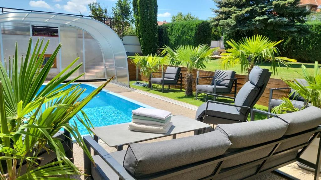 eine Terrasse mit einem Pool, Stühlen, einem Tisch und einem Pool in der Unterkunft Villa Nova in Hévíz