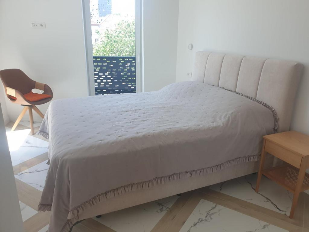 a bed in a bedroom with a chair and a window at PALAR Apartment in Ljubljana