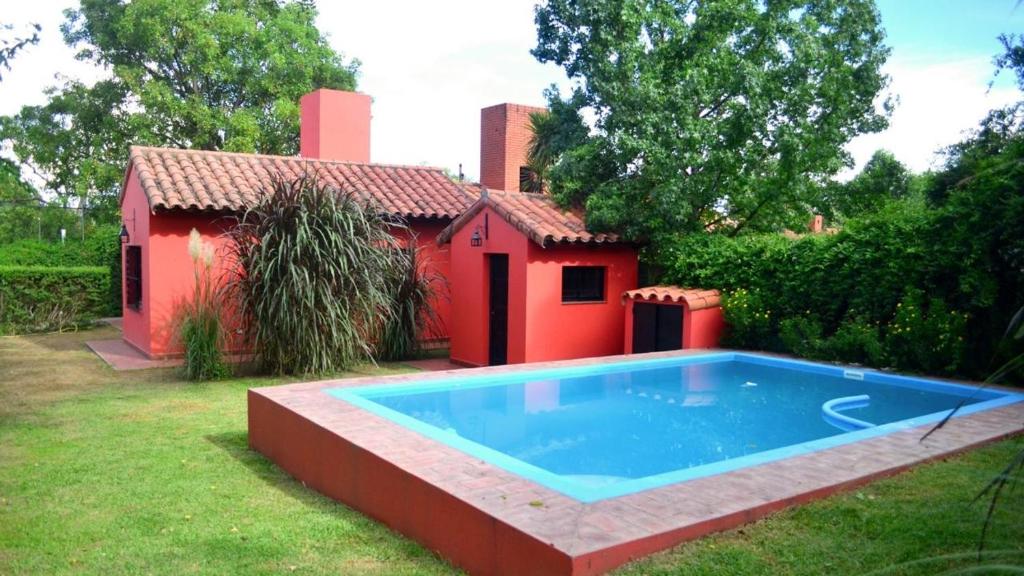 una casa rossa con piscina nel cortile di Pirpintos, Cabanas de San Lorenzo a San Lorenzo