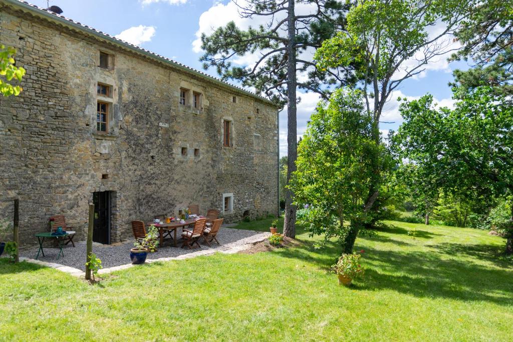 - un bâtiment en pierre avec une table et des chaises dans une cour dans l'établissement Maison d'Hôtes Mas de la Chadenede, à Lagorce