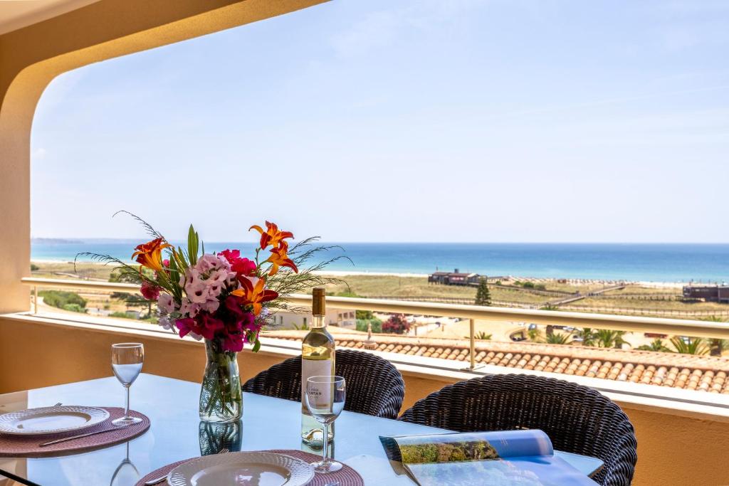 un tavolo con un vaso di fiori e una vista sull'oceano di Vila Palmeira Beach Resort a Lagos