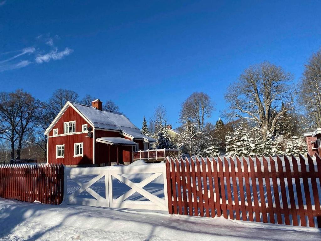 a red house with a fence in the snow at Haus Vitsippan in Mariannelund