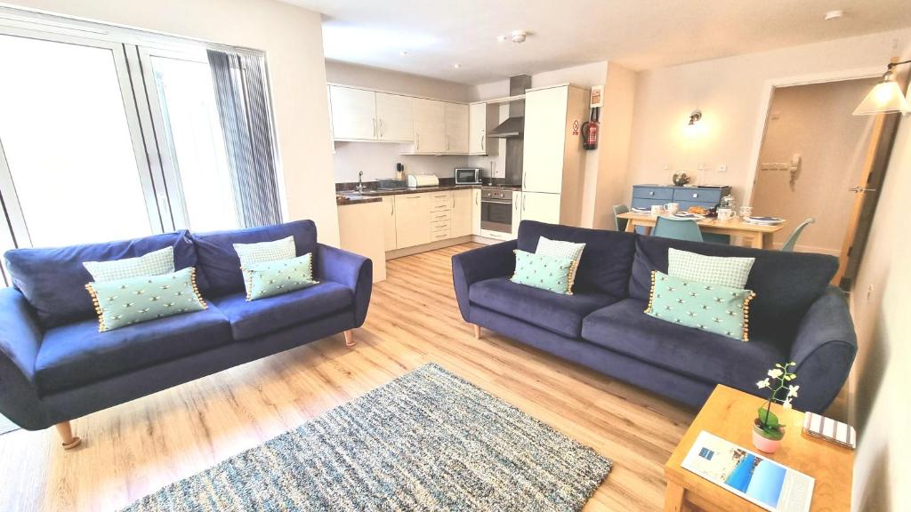 sala de estar con 2 sofás azules y cocina en The Beach House & Porth Sands Apartments, en Newquay