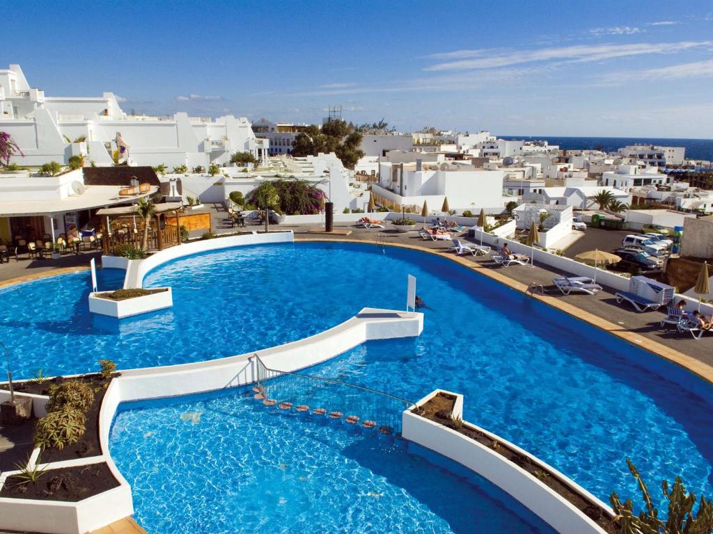 a large pool with blue water and white buildings at BelleVue Aquarius in Puerto del Carmen