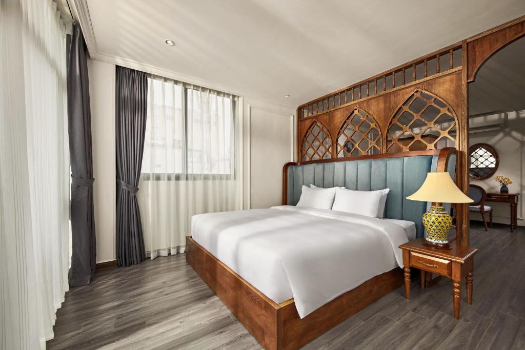 a bedroom with a large bed with a wooden headboard at Eliana Premio Hotel Hanoi in Hanoi