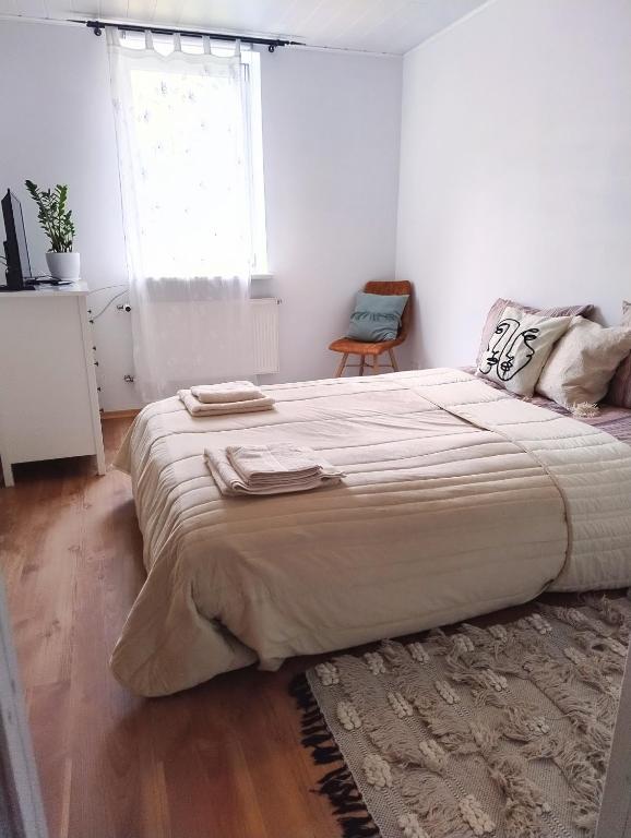 een groot bed in een witte kamer met een raam bij GreenHill House in Kaunas