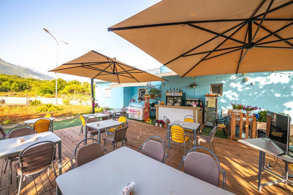 a restaurant with tables and chairs and umbrellas at Blu Horizon Hotel Gjipe in Dhërmi