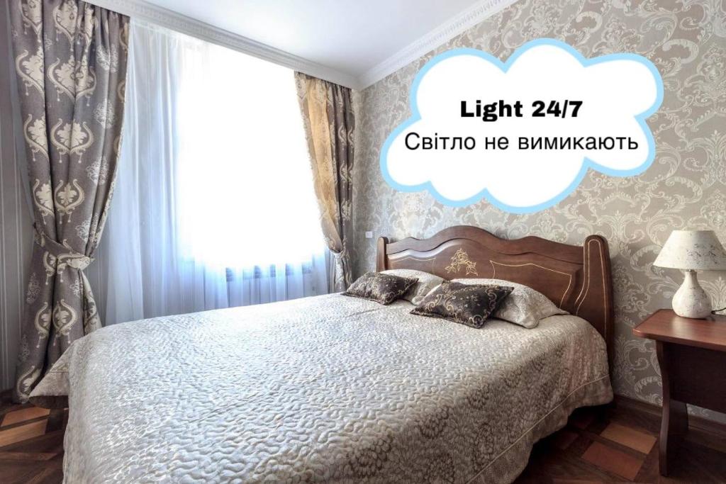 - une chambre avec un lit et un panneau lumineux au-dessus dans l'établissement Apartment Ryadom S Ploshadiu Rynok, à Lviv