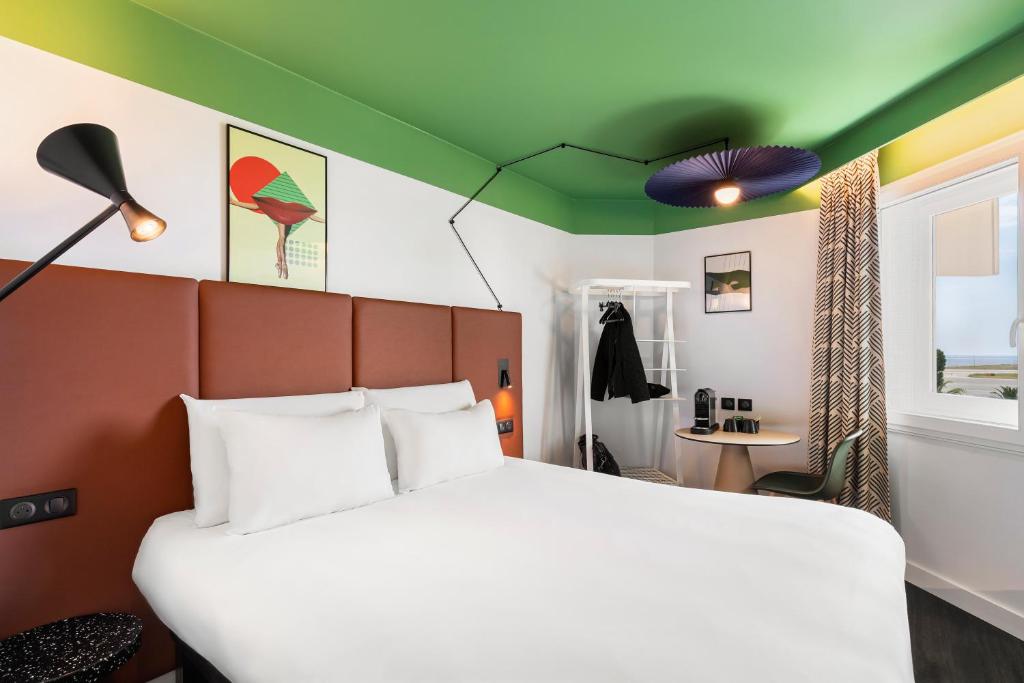 um quarto com uma cama branca e um tecto verde em ibis Nice Aéroport Promenade des Anglais em Nice