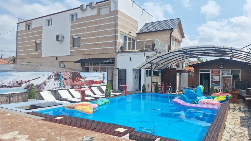 einem großen Pool mit aufblasbaren Gegenständen vor einem Gebäude in der Unterkunft Apartments Vila Brzi & Beka in Šabac