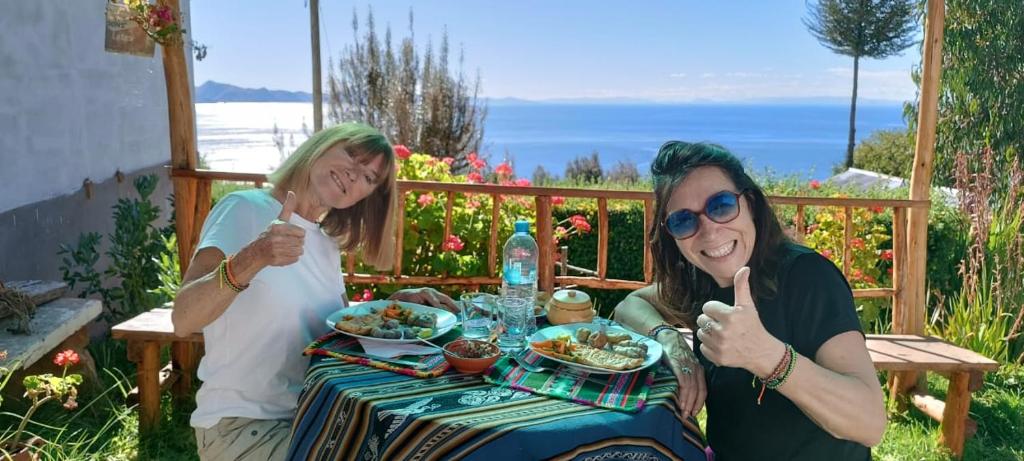 dos mujeres sentadas en una mesa comiendo comida en Amantani Resorts, en Estanciasuyo