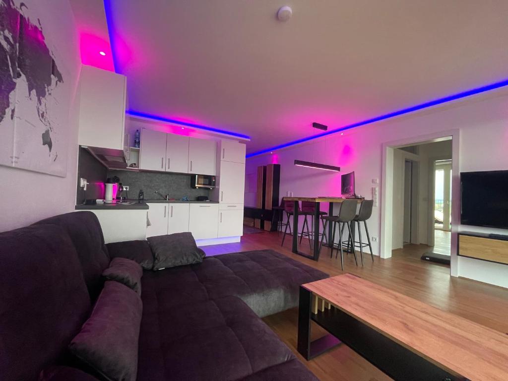 un soggiorno con divano e una cucina con luci rosa di 100 qm Penthouse, Self-Check-In, 2 Parkplätze a Graz