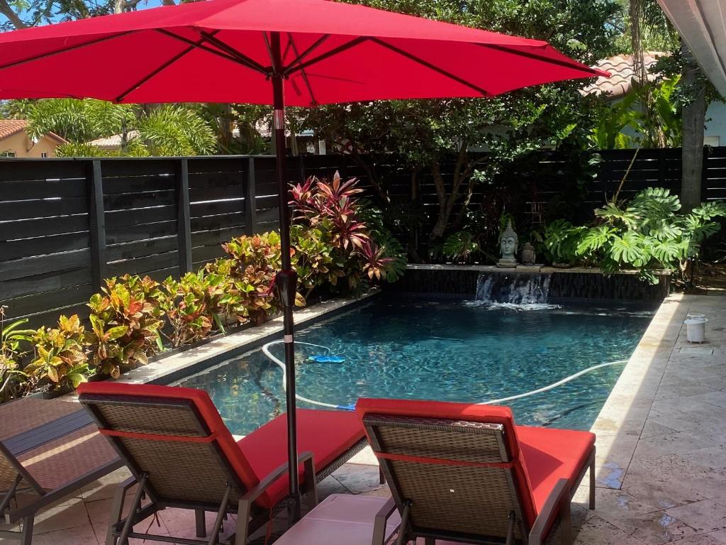 - un parasol rouge et des chaises à côté de la piscine dans l'établissement Riverbank Guesthouse Wilton Manors, à Fort Lauderdale