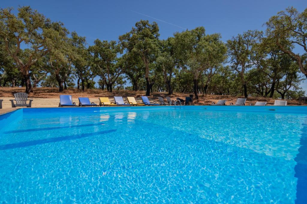 uma piscina com cadeiras e árvores ao fundo em Valle D`Água - Casas de campo em Vale de Água