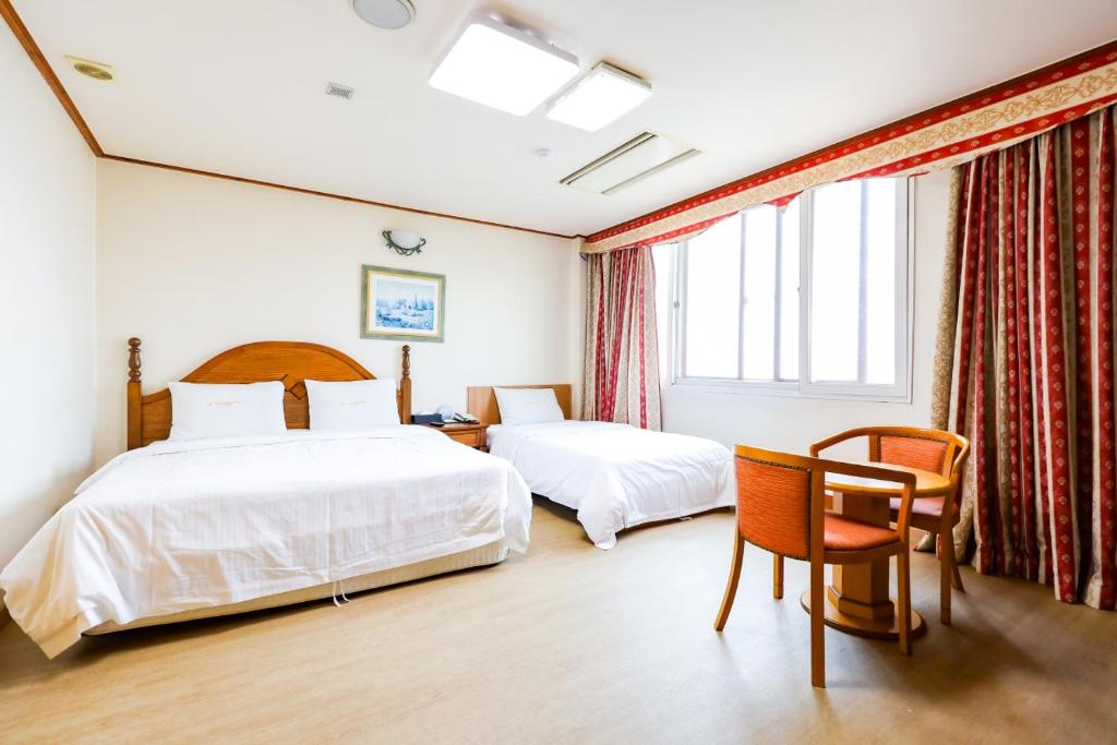 a hotel room with two beds and a chair at Newvera Hotel in Cheongju